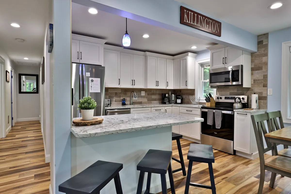A stylish kitchen with a granite countertop island, stainless steel appliances, and a wooden dining table set for casual dining or entertaining. The design is modern and functional, encouraging group cooking or celebratory brunches.