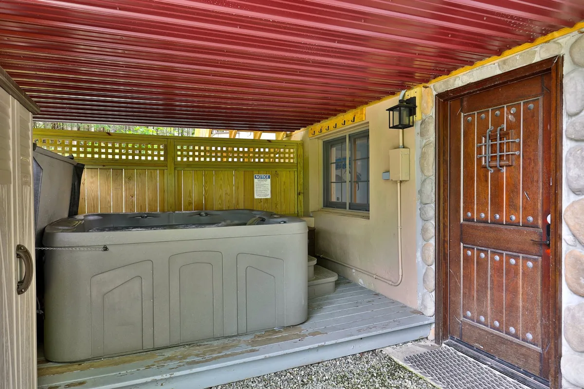 A cozy indoor hot tub area featuring a wooden door and a rustic stone wall. The ambient lighting and design invite guests to soak and relax in a private, intimate setting—ideal for star-lit evenings or warming up after winter sports.